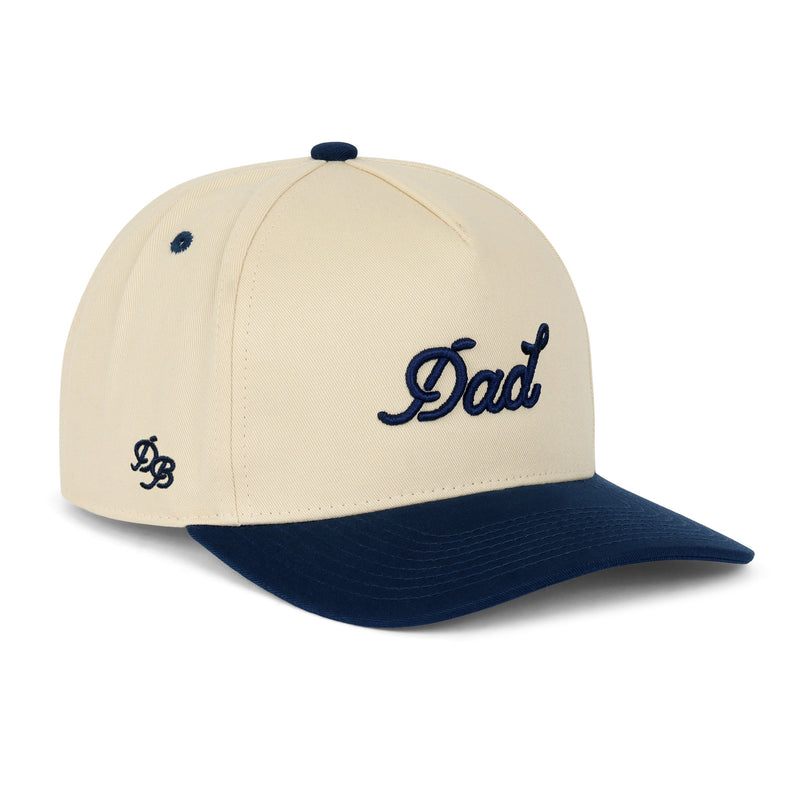 Dad Snapback Hat – Cream and navy snapback with 3D embroidered “Dad” logo. Structured five-panel hat and funny gift idea for dads from Dad Brand.